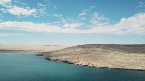 Las-Dunas-Del-Desierto-De-Namib-Y-El-Océano-Atlántico-Se-Encuentran,-La-Costa-De-Los-Esqueletos,-El-Sur-De-áfrica-Namibia,-La-Toma-Aérea-De-La-Isla-De-Los-Tiburones-De-La-Ciudad-De-Luderitz