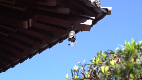 The-iron-bell-hanging-top-roof-in-a-Chinese-temple,-ringing-by-wind