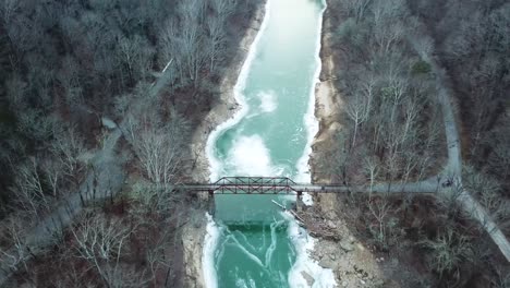 Rostige-Fußgängerbrücke-über-Den-Eisigen-Gebirgsfluss