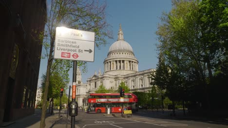 static shot of st. paul cathedral, traffic sign and a red bus passing through the empty junction