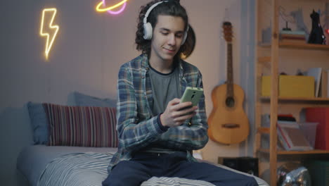 teenager listening to music and using smartphone in bedroom
