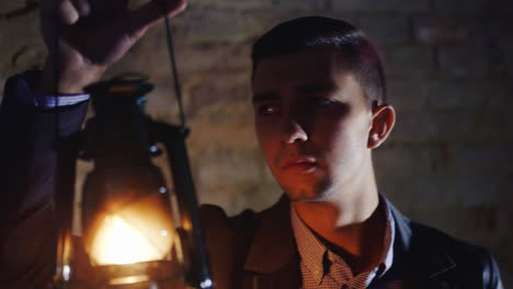 Scared-Young-Man-In-A-Dark-Hallway-Holding-An-Oil-Lamp-In-His-Hand-Dressed-In-A-Suit