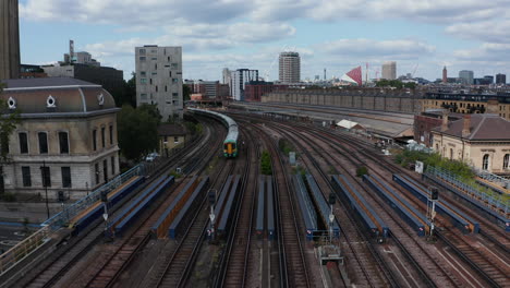 Backwards-tracking-of-passenger-train-driving-on-wide-multitrack-railway-bridge-over-river.-London,-UK