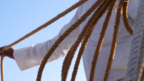 detail of traditionally dressed man preparing ropes for a boat ride in aswan, egypt