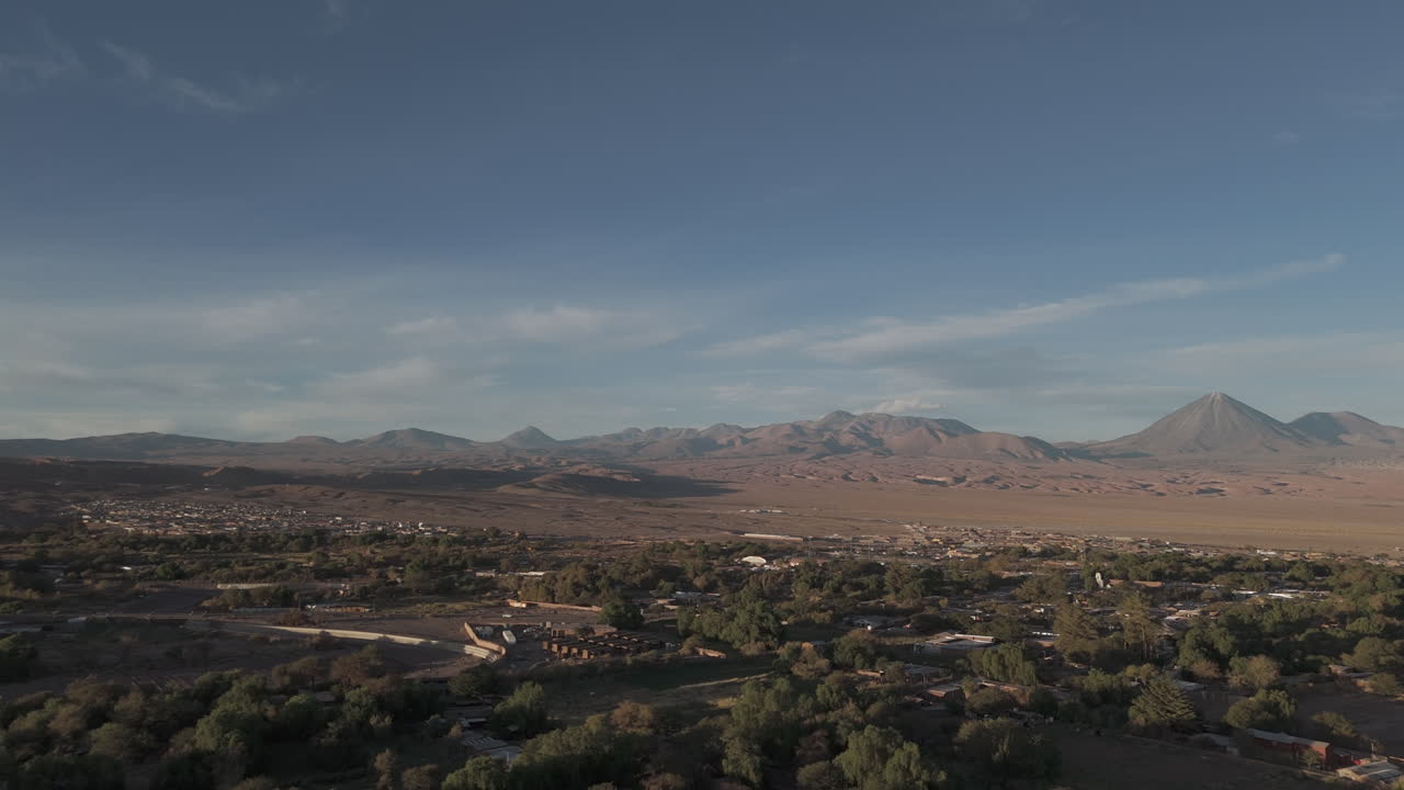 Sideways flying drone shot above San Pedro de Atacama Chile South America on a blue but cloudy day with mountains in the background LOG