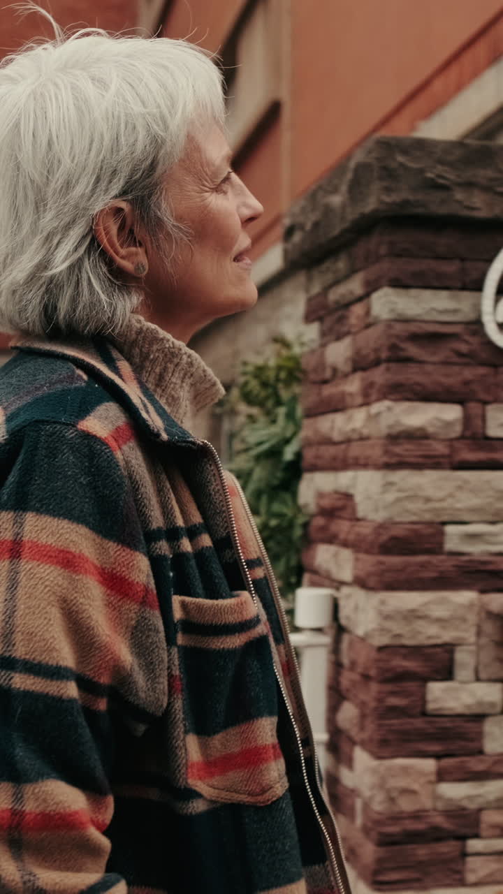 Donna anziana che passeggia all'aperto con una giacca a quadri