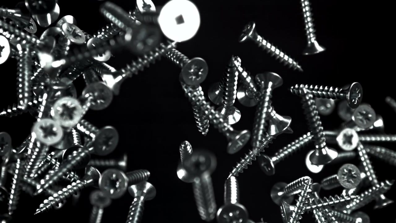 黒い背景に光沢のある金属製のネジが浮かぶクローズアップ