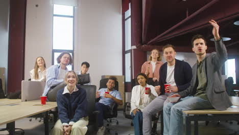 group of multiethnic colleagues watching a sportive match, cheering and supporting their team at the office 2