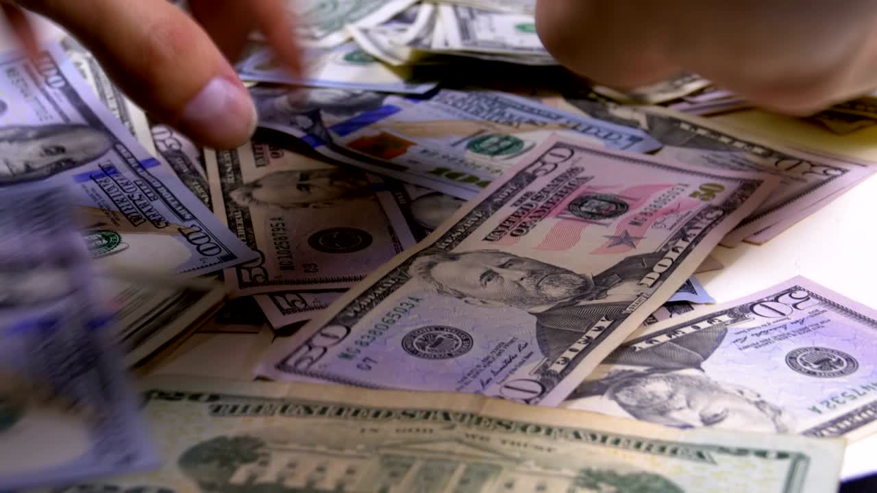 las manos de los hombres se recogen en el montón de dólares estadounidenses de varias denominaciones