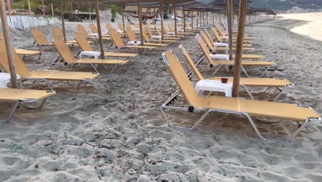 view on orange vacant sunbeds under straw sun umbrellas due to covid-19 travel ban and economic recession in 4k