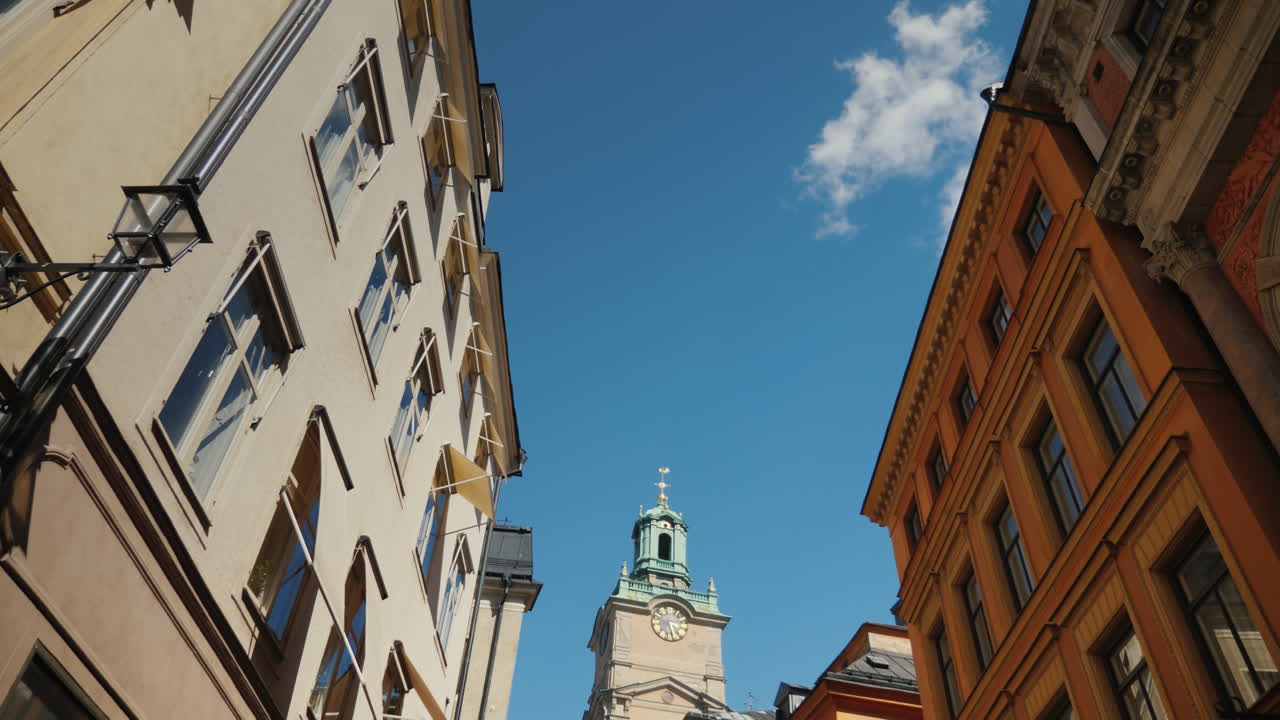 스톡홀름의 세인트 니콜라스(storkyrkan) 종탑은 오래된 집이 있는 좁은 거리를 통해 볼 수 있습니다. 4k vid
