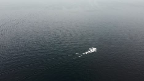 Clockwise-drone-shot-of-a-jet-ski-driving-on-Payette-Lake-in-McCall,-Idaho-on-a-smoky-day