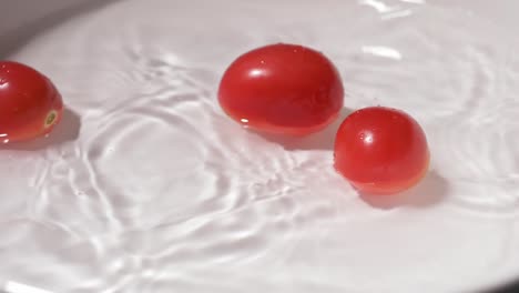 Tomates-Pequeños-Que-Caen-En-Un-Recipiente-Con-Agua-Para-Limpiar