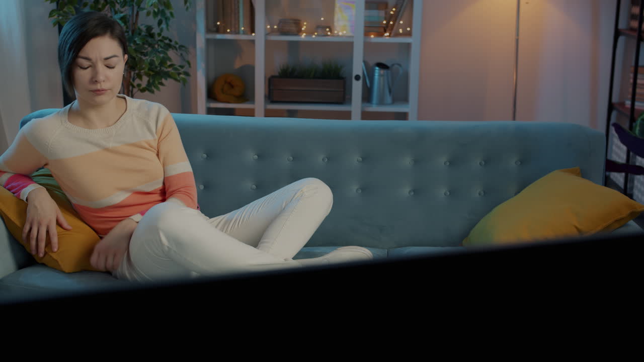 여자 가 소파 에서 휴식을 취 하고 tv 를 보고 있다
