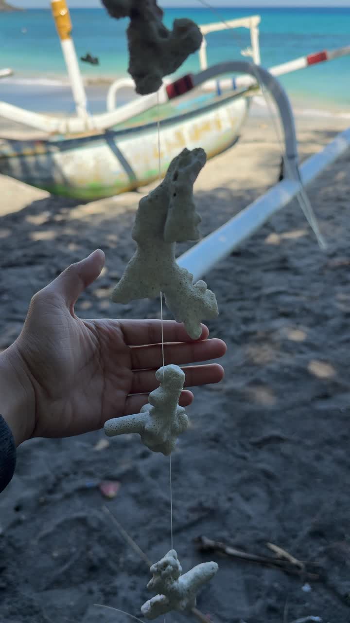 Mano di una persona che tiene pezzi di corallo su una spiaggia tropicale