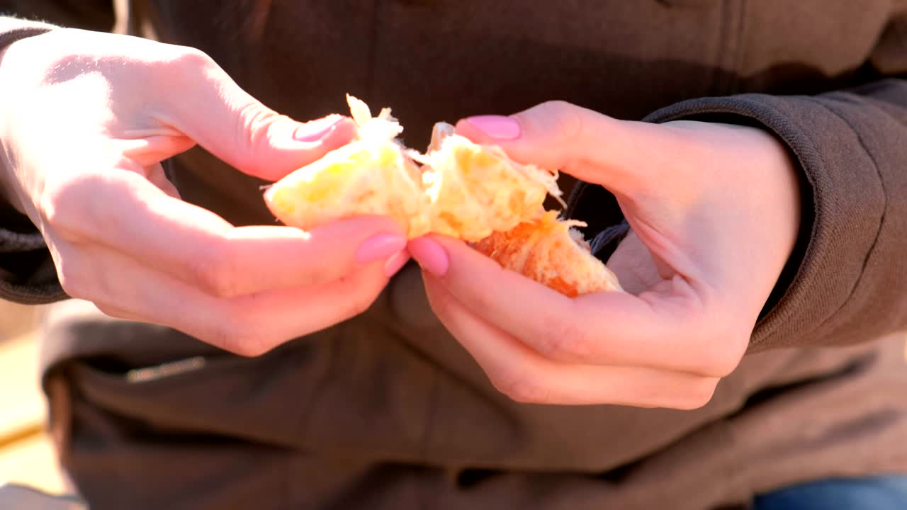 Close-up woman's hands divide the tangerine into slices.
