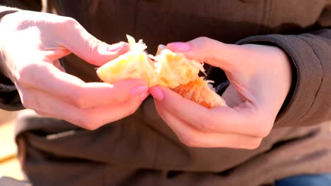 close-up woman's hands divide the tangerine into slices.