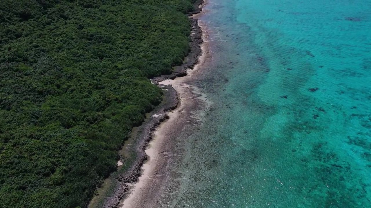 Carrellata orizzontale in avanti da un'angolazione elevata verso il basso, rivolta a sinistra, sulla costa turchese dell'isola di Kurima, Okinawa, Giappone