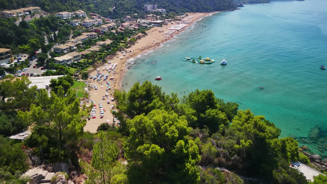 Aerial view of lush green forest next to turquoise sea on a sunny day