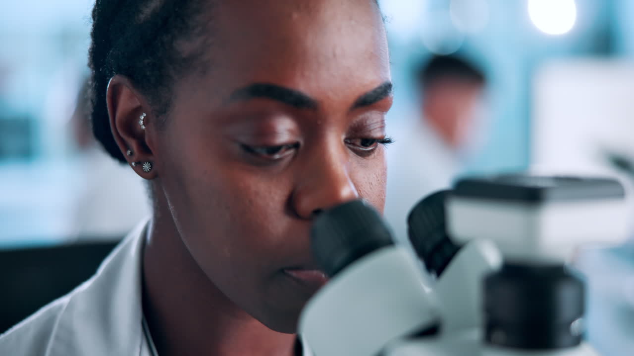 Científica mujer mirando a través del microscopio