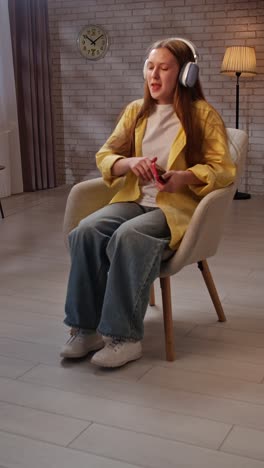 teenage girl dancing to music while sitting on chair