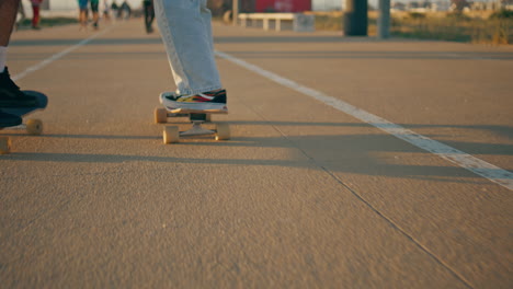 couple skaters riding skateboards at city promenade. pair shoes standing boards