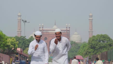 hombres musulmanes haciendo adab frente a una mezquita a la cámara