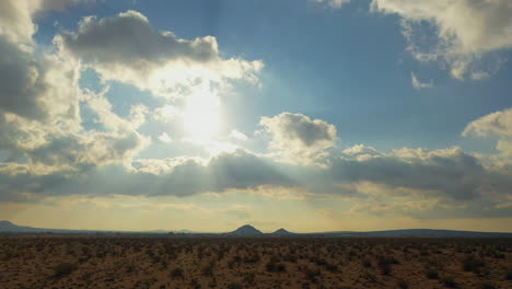 the mojave desert landscape with storm clouds forming in the sunny sky - subtle push forward aerial view