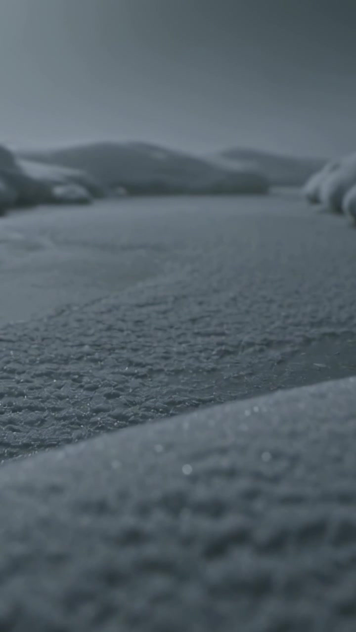 Vertical video: Pulling back camera revealing frost crystals and frozen plain with rounded drifts