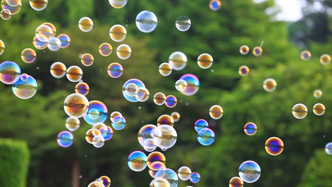 burbujas de jabón flotando en el aire con fondo bokeh verde natural borroso para el diseño de la infancia