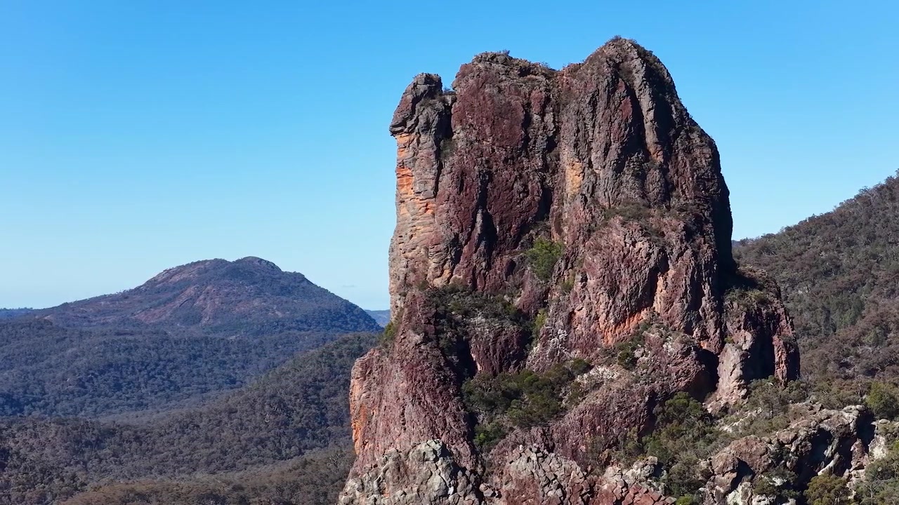 Statisk vidvinkelbillede af forrevne vulkanske tinder under klar blå himmel i Warrumbungle Nationalpark