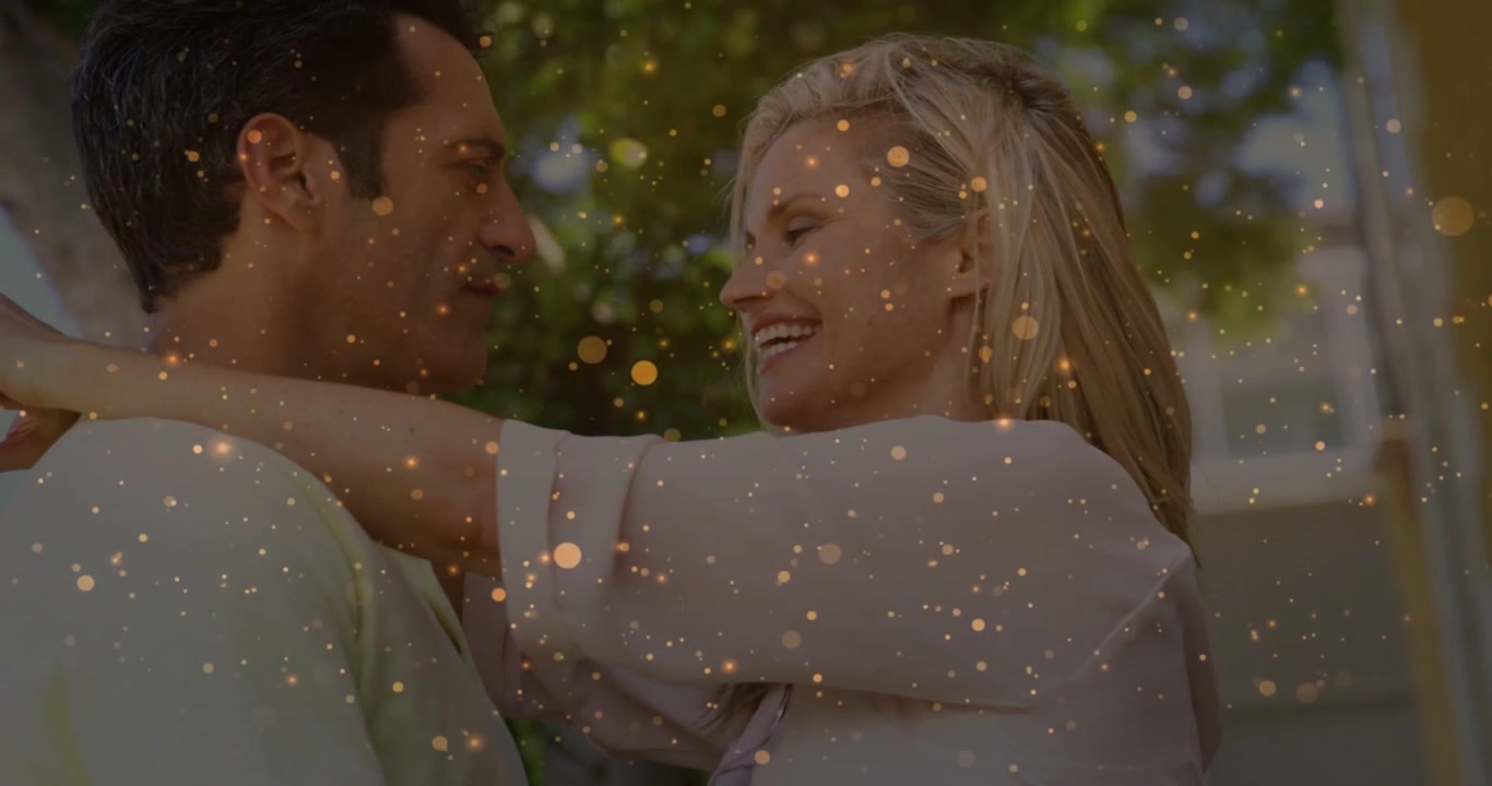 Frau lehnt sich an Mann, ein Paar lacht gemeinsam für eine Lifestyle-Werbung, während goldenes Bokeh über ihre Gesichter gleitet.
