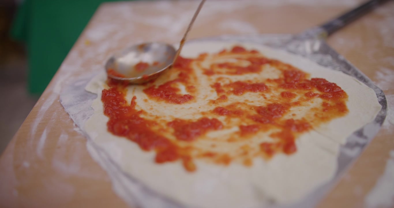 Spalmare la salsa di pomodoro sulla pasta fresca della pizza