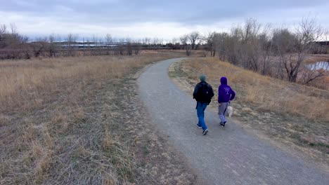 a wintry path is the destination for a  man and his son as they walk a tiny dog along its bleak length.