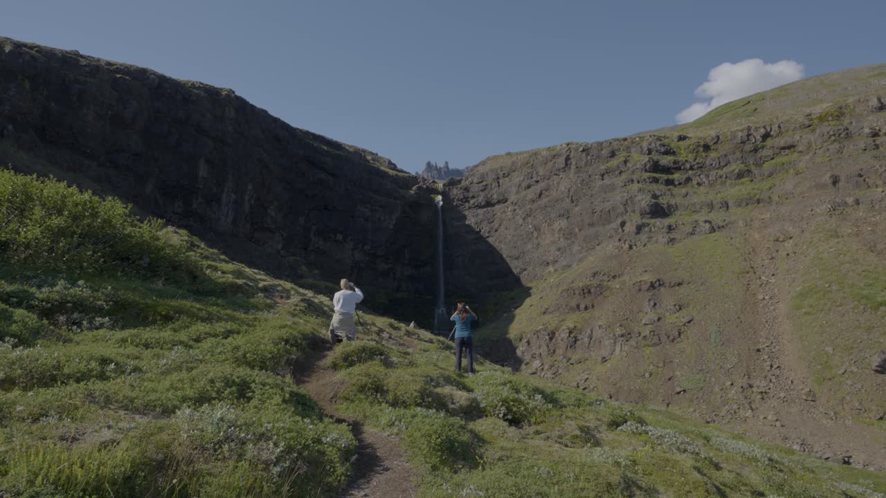 fotógrafo tomando fotos de la gigantesca cascada de flo gufoss durante un día soleado en el este de islandia