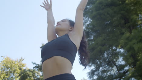 ángulo-Bajo-De-Una-Hermosa-Joven-Que-Termina-El-Ejercicio-De-Yoga-En-Un-Parque-Soleado