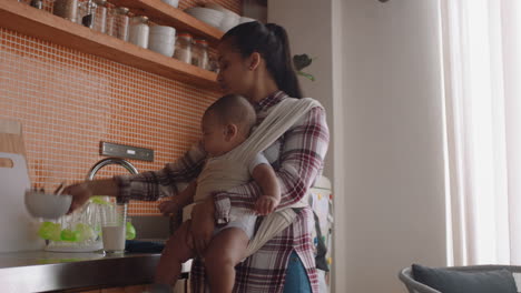 madre joven sosteniendo a su bebé trabajando en casa limpiando la cocina cuidando al bebé disfrutando de la maternidad