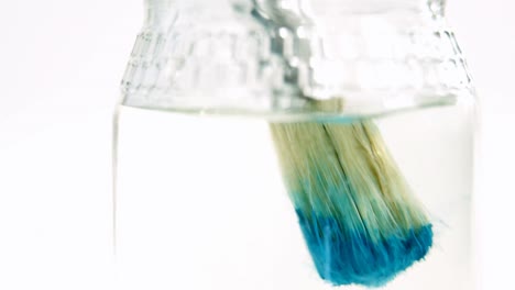 Close-up-of-paintbrush-with-blue-paint-being-washed-in-water