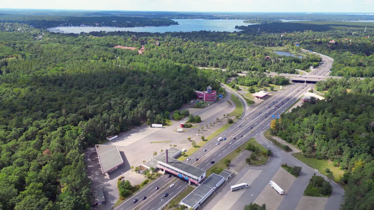 Cars driving on a freeway interchange surrounded by forest leading to a lake on a cloudy day. Spectacular aerial view flight speed ramp hyper motion time lapse