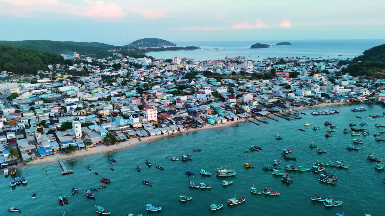 Aerial: fisher village with cable cars and fish boats during the day in Sunset Town, Phu Quoc Island, Vietnam, orbit drone shot