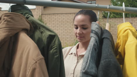 woman choosing second hand clothes at yard sale