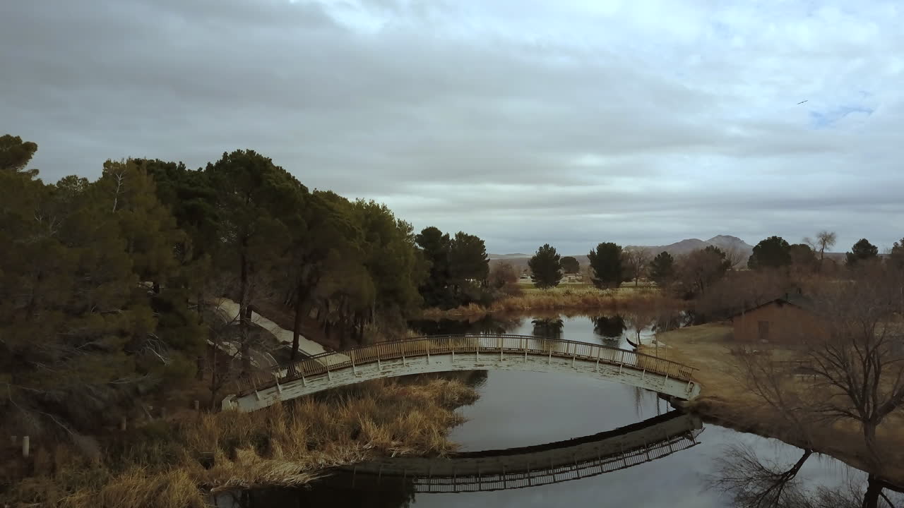 antena, volando hacia un puente de madera sobre un lago en un día nublado de otoño, california