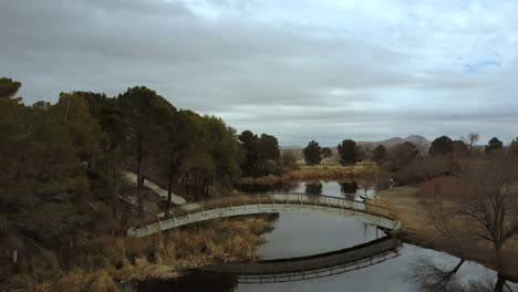 aerial, flying toward a wooden bridge over a lake on a cloudy fall day, california