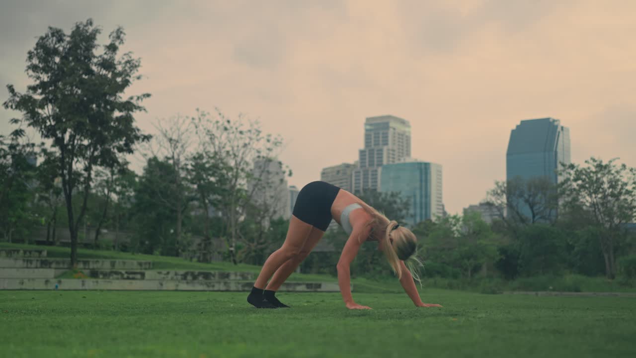 Fit young blonde female doing yoga poses in Benchakitti Park Bangkok Thailand