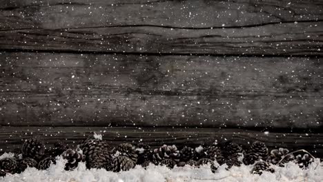 animation of christmas snow falling over wooden boards and pine cones