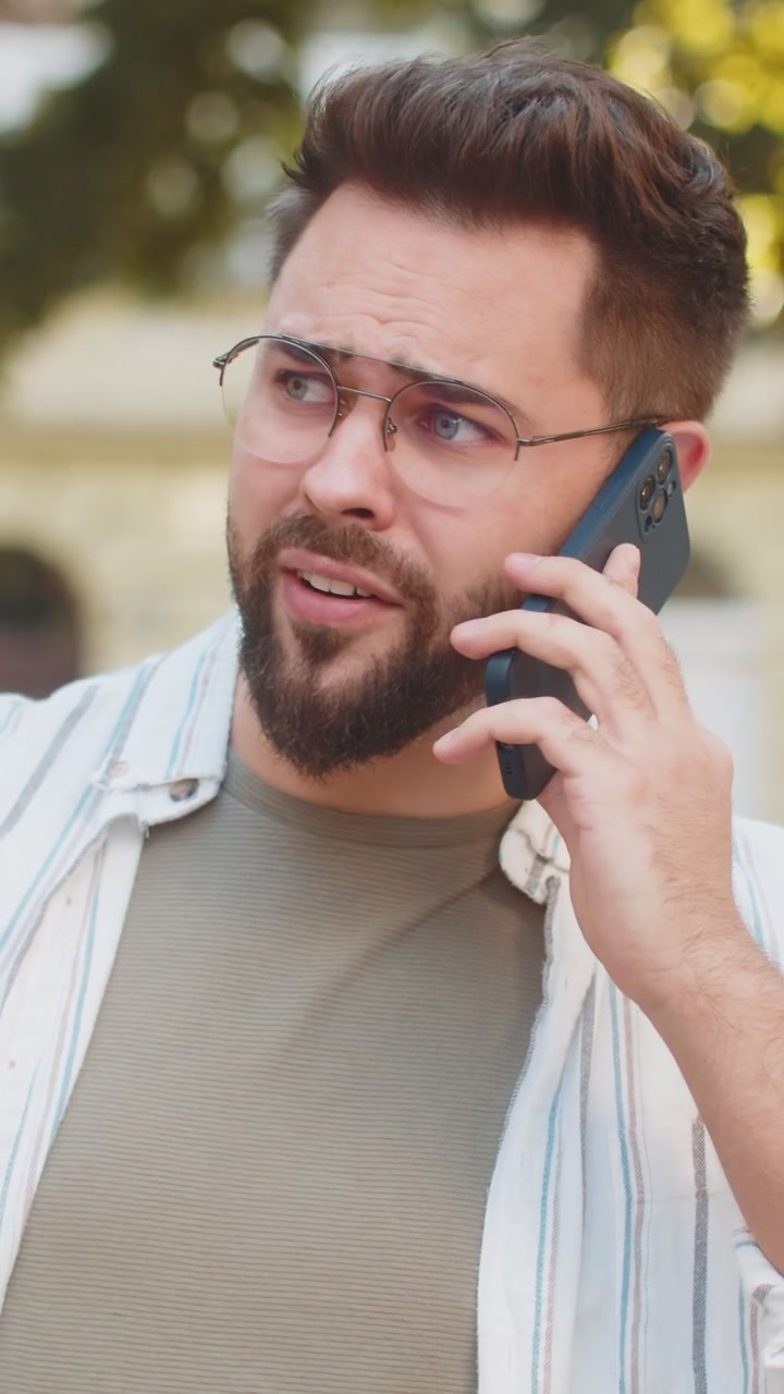 Un joven viajero caucásico discutiendo hablando en su teléfono inteligente mientras camina por la calle de una ciudad urbana