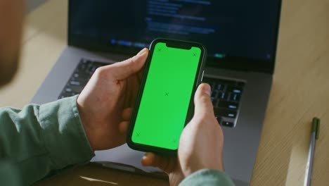 un joven se desplaza por la pantalla verde de un teléfono móvil, copia el espacio