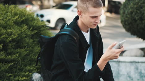 young student using mobile phone outdoors.