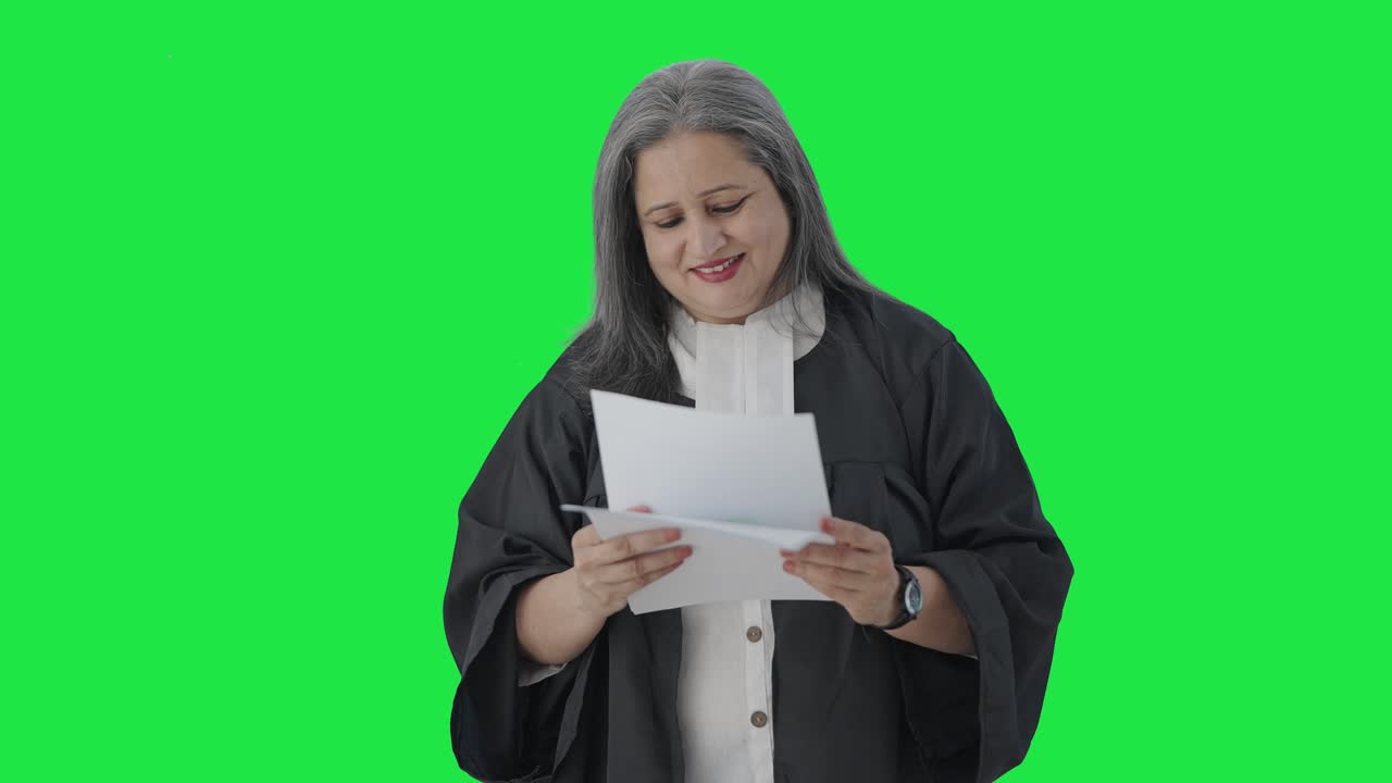 Avvocatessa indiana anziana felice che legge rapporti di casi su schermo verde