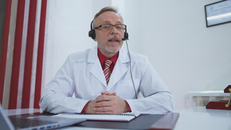 doctor working on line with laptop. senior doctor having video chat with patient on laptop